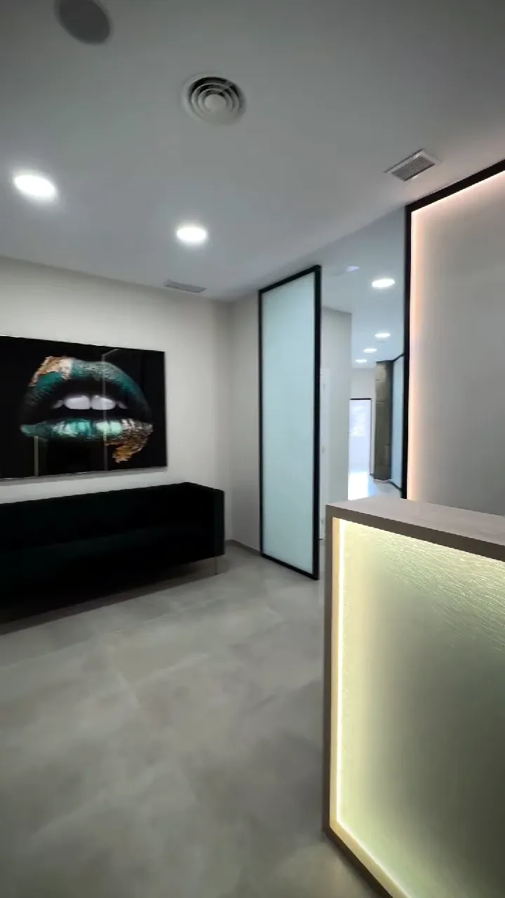 Sala de espera con sofá verde junto a la recepción